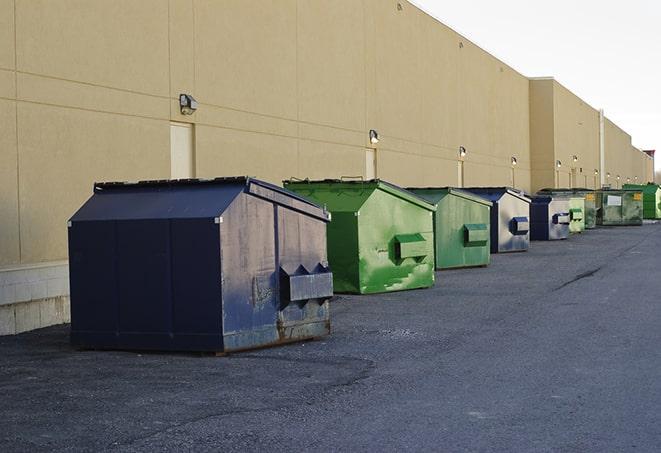 a team of workers hauls broken concrete in wheelbarrows to the dumpster in Clint